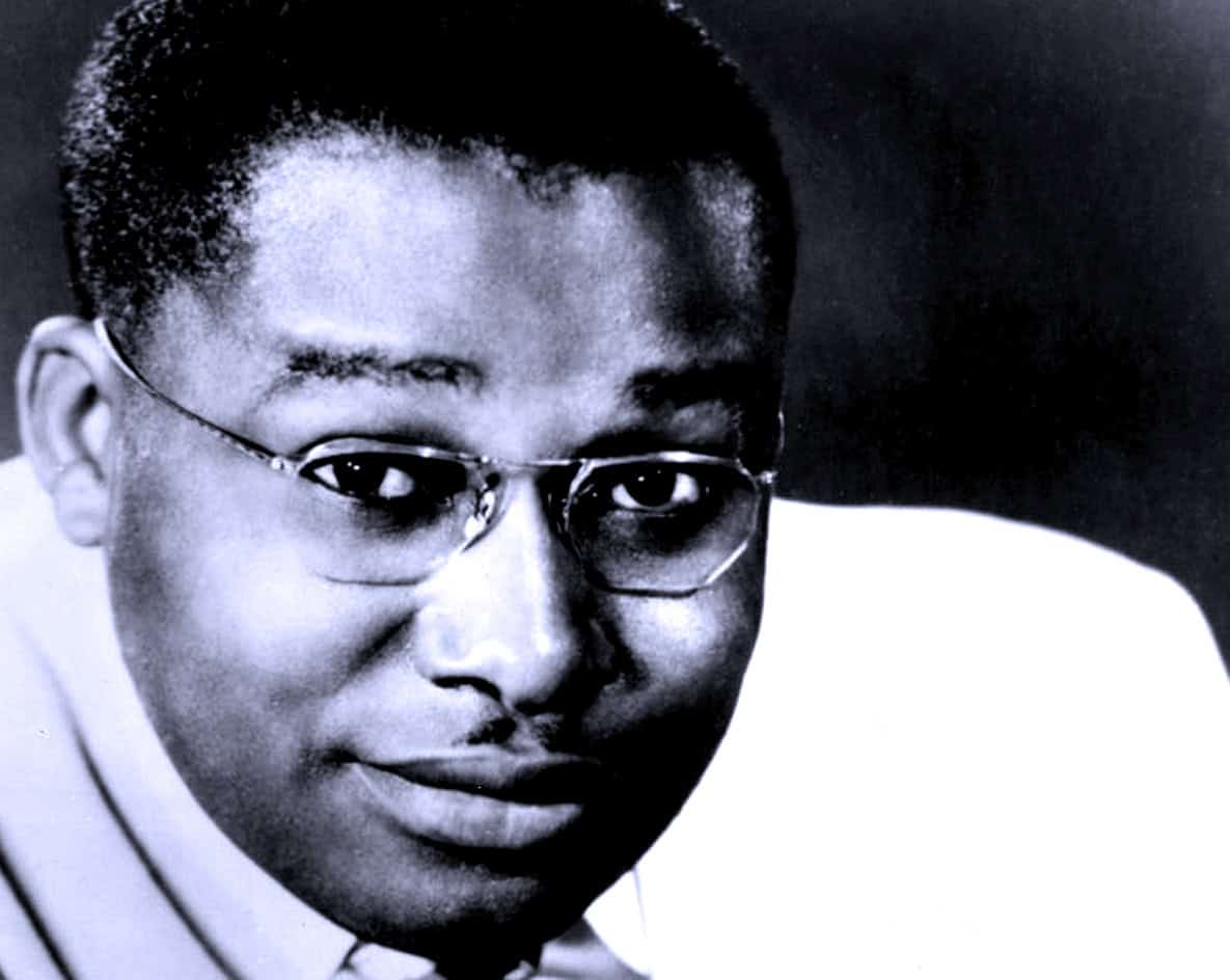 Insightful black and white portrait of a jazz musician or historical figure, emphasizing their expressive eyes and glasses, relevant to news, history, and music archives.
