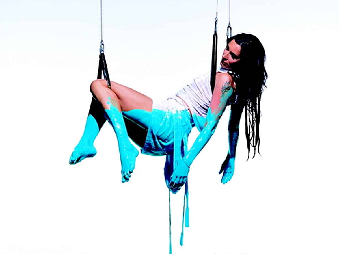 Vintage aerial silk performer acrobat in vibrant blue costume demonstrating aerial arts and circus entertainment.