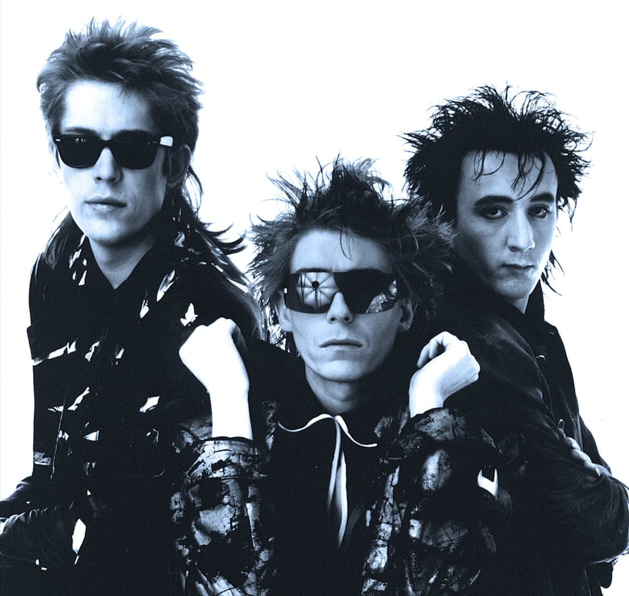 Vintage punk rock band photograph featuring three members with spiky hair and dark sunglasses, emphasizing alternative music and 1980s music culture.