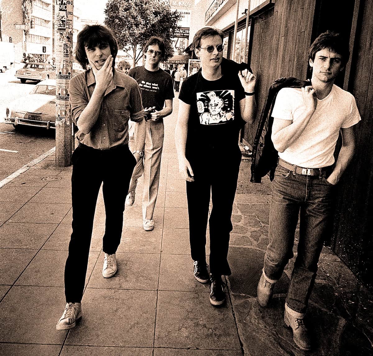 Chic young adults walking on city sidewalk, representing 80s / 90s pop culture, fashion, and music influence, captured in a vintage-style photo.