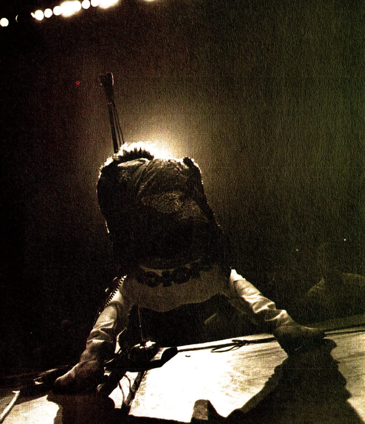 Watching performer on stage with bright backlight and vintage grainy effect, capturing the essence of music history and nostalgic concert moments, representative of the Past Daily sound archive of news and music.