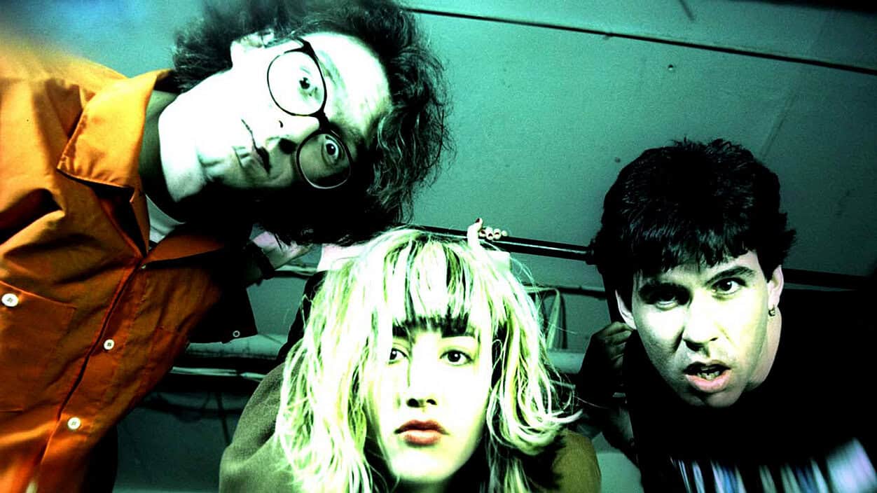 The band in the photo has a vibrant, retro aesthetic with bold colors and expressive poses, emphasizing music and pop culture themes.