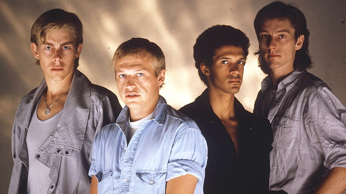 Teen idols from the 1980s, dressed in casual denim and leather, posing for a promotional photo, representing pop and rock music culture of that era.