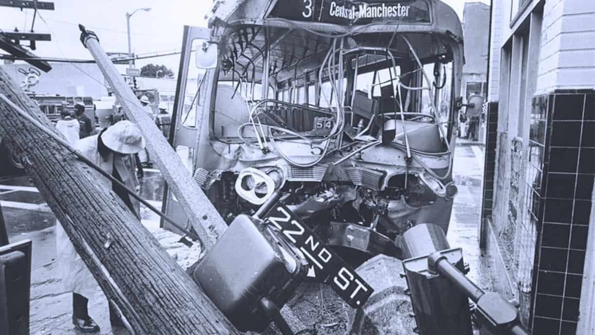 Bus accident aftermath with a damaged bus and fallen utility pole, showing urban destruction and emergency scene.