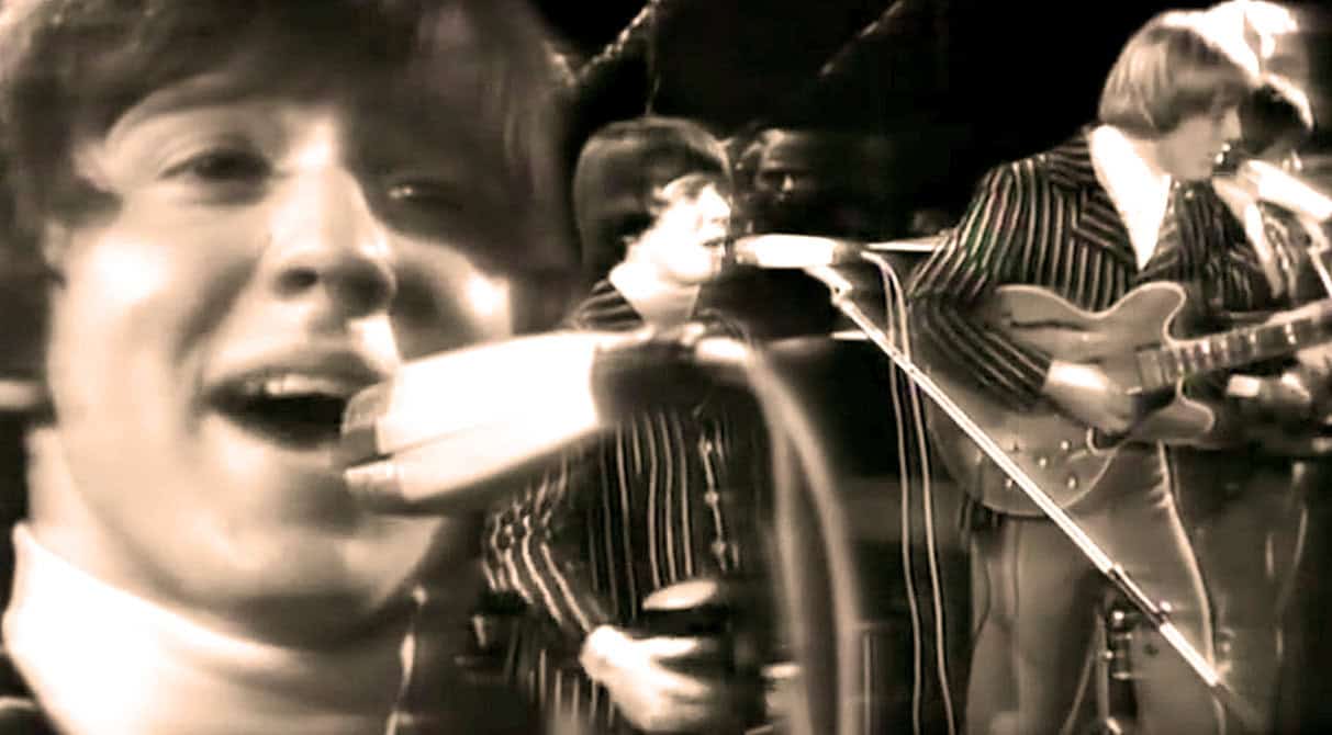 Vintage rock band performing live music session with guitars and microphones for historical music archive.