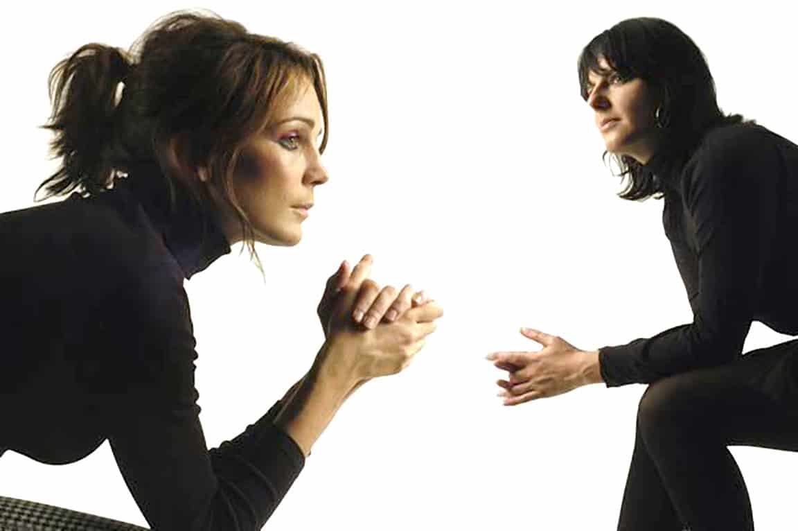 Woman praying with hands clasped, woman talking to woman, emotional conversation, support and empathy, black attire, relationship, communication, stress, mental health, Past Daily news and history archive.