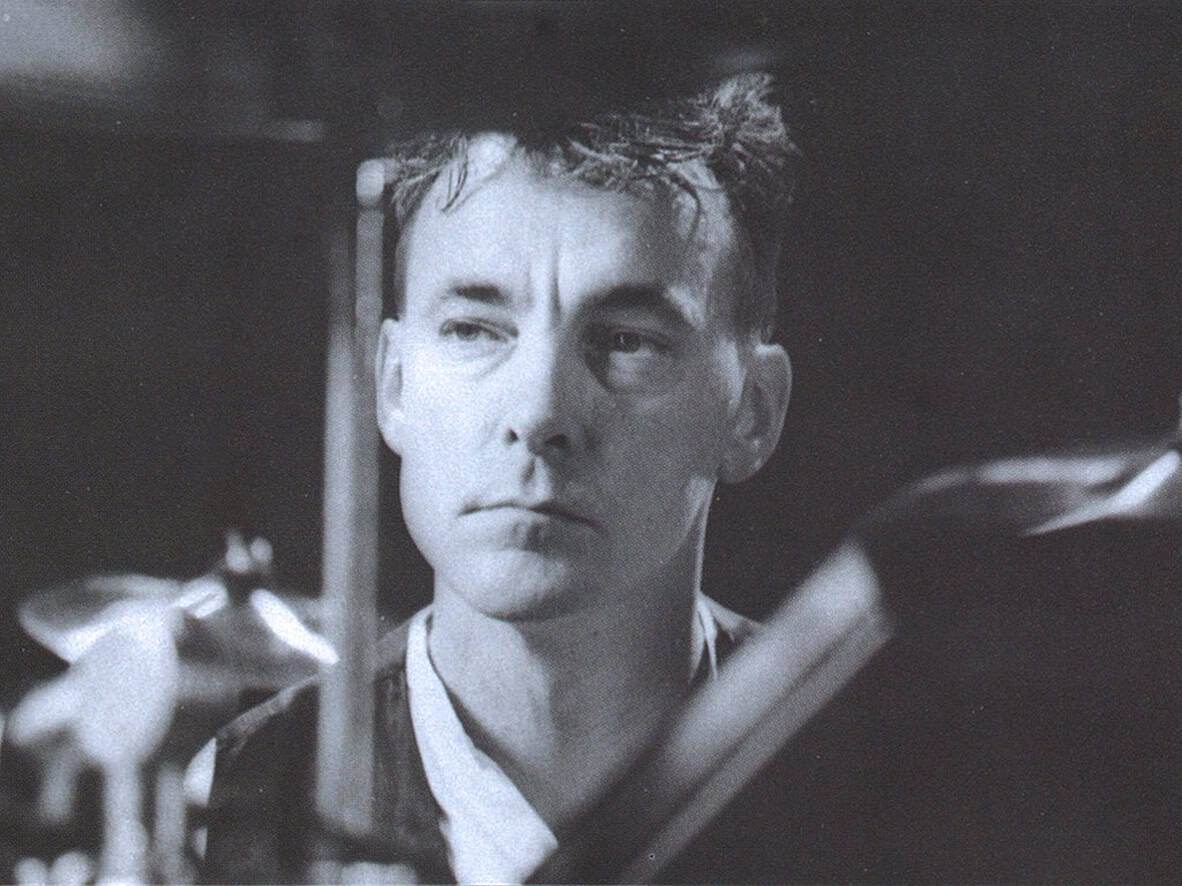 Black and white photo of a young man with a serious expression, recording or listening to music, representing historical sound archives and vintage audio recordings.