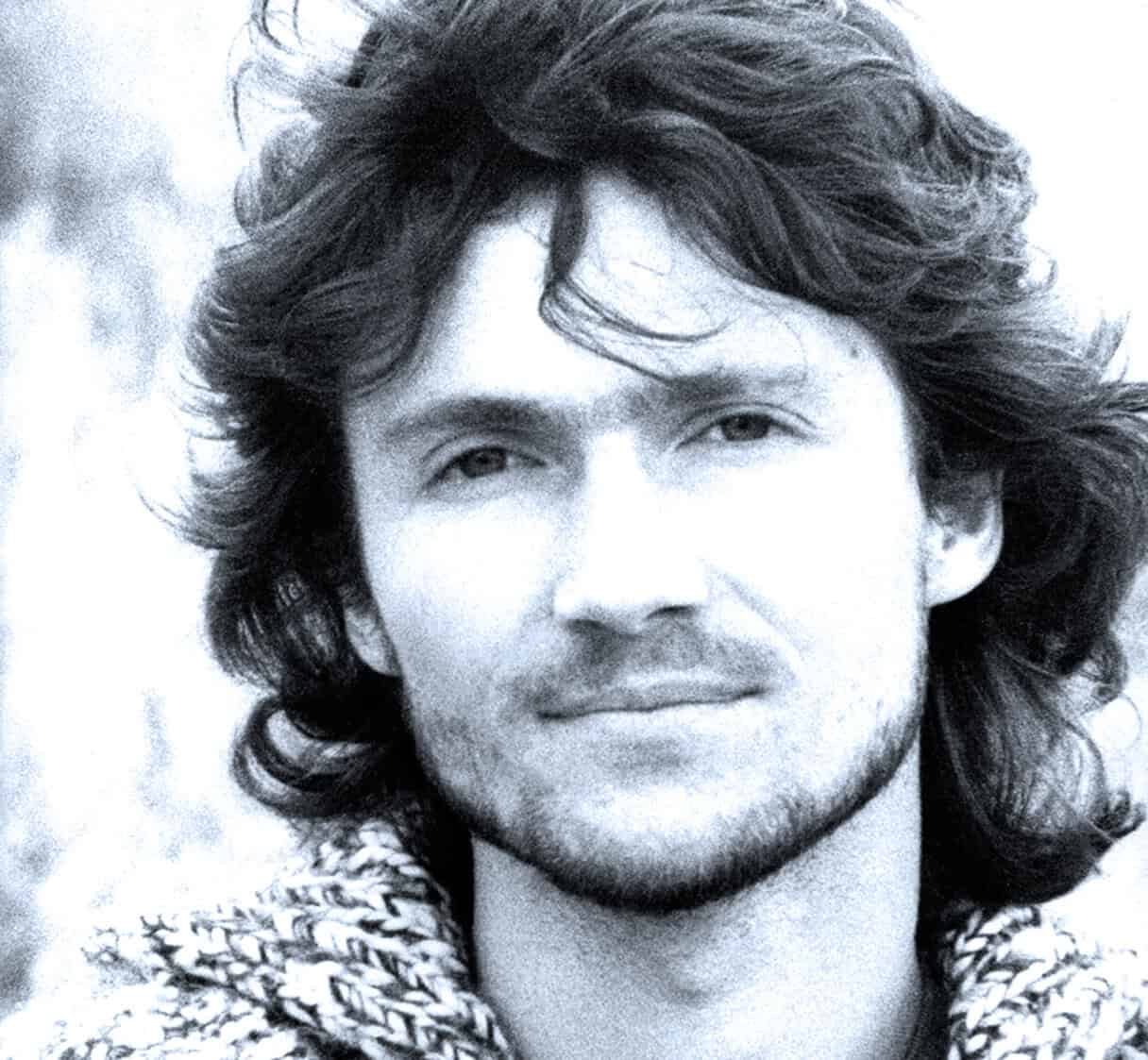 Portrait of a young man with long, wavy hair, capturing a nostalgic and vintage vibe, associated with classic music and radio archives from Past Daily.