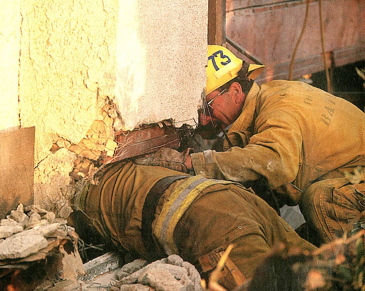 Firefighters rescuing victim from building collapse after earthquake, emergency workers at disaster site, urgent rescue operation, disaster response, urban emergency rescue efforts.