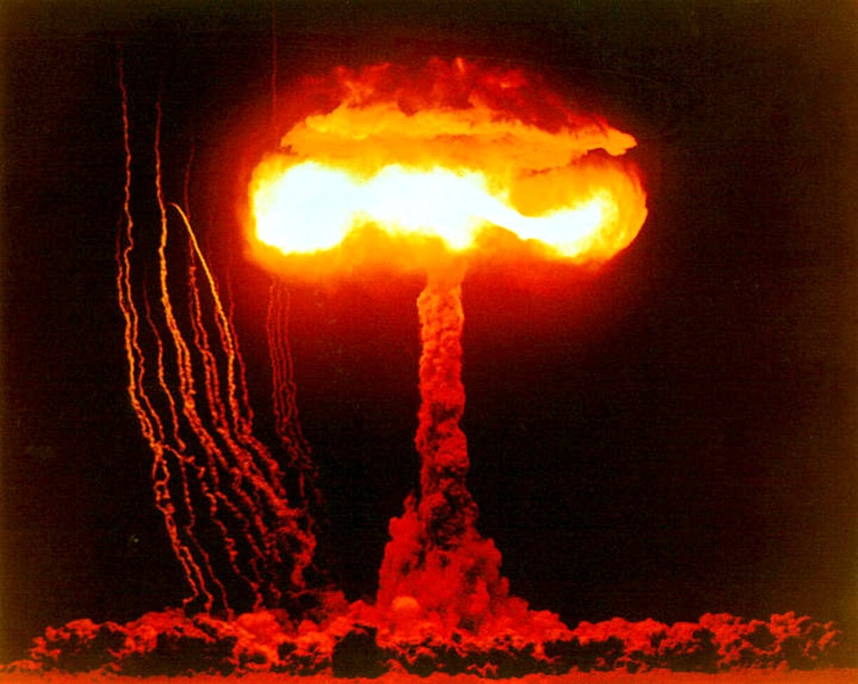 Nuclear explosion mushroom cloud with fiery orange and bright yellow colors, depicting a devastating nuclear blast and its impact on history and world events.