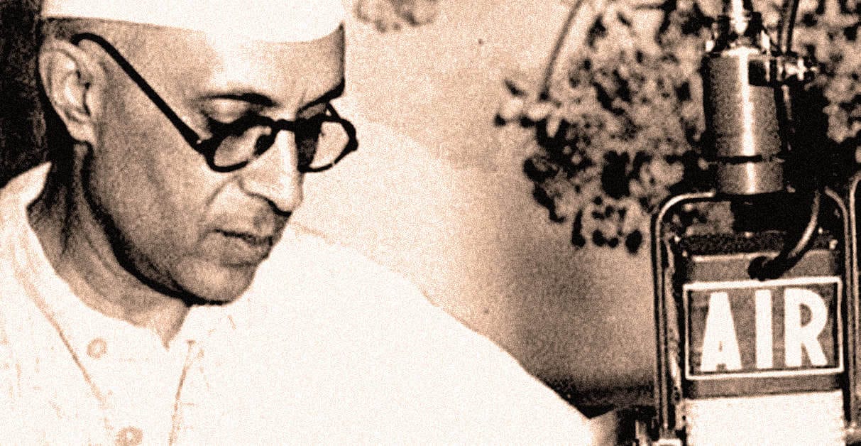 Classic black-and-white photo of a radio broadcaster with glasses at a vintage microphone, representing historical news, music, and radio broadcast archives on Past Daily.