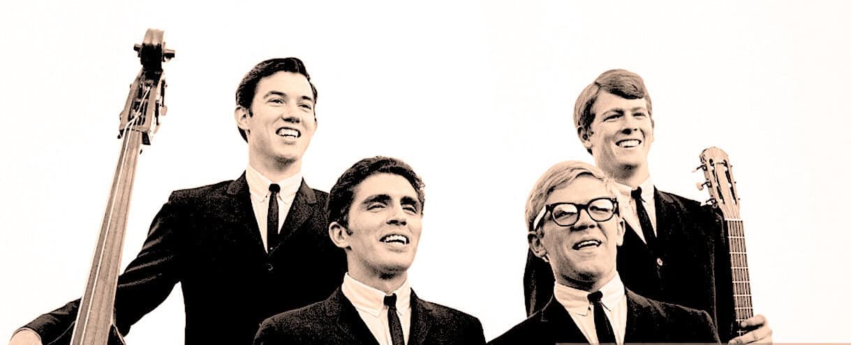 Vintage band members with guitars, black suits, and ties, representing musical history and classic rock, on a white background for nostalgia, music archives, and historical news coverage.