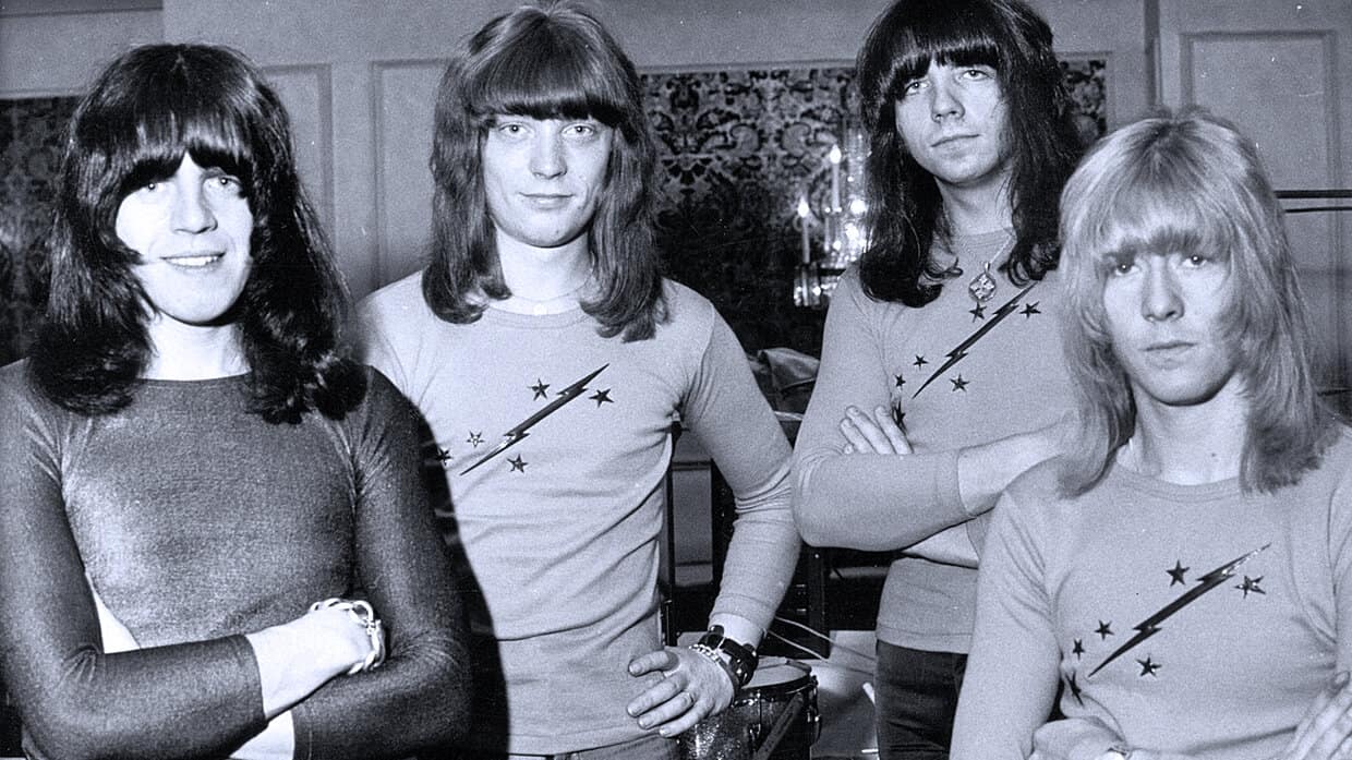 Members of the band The Runaways in a black-and-white photo, showcasing classic rock music history and iconic female musicians from the 1970s.