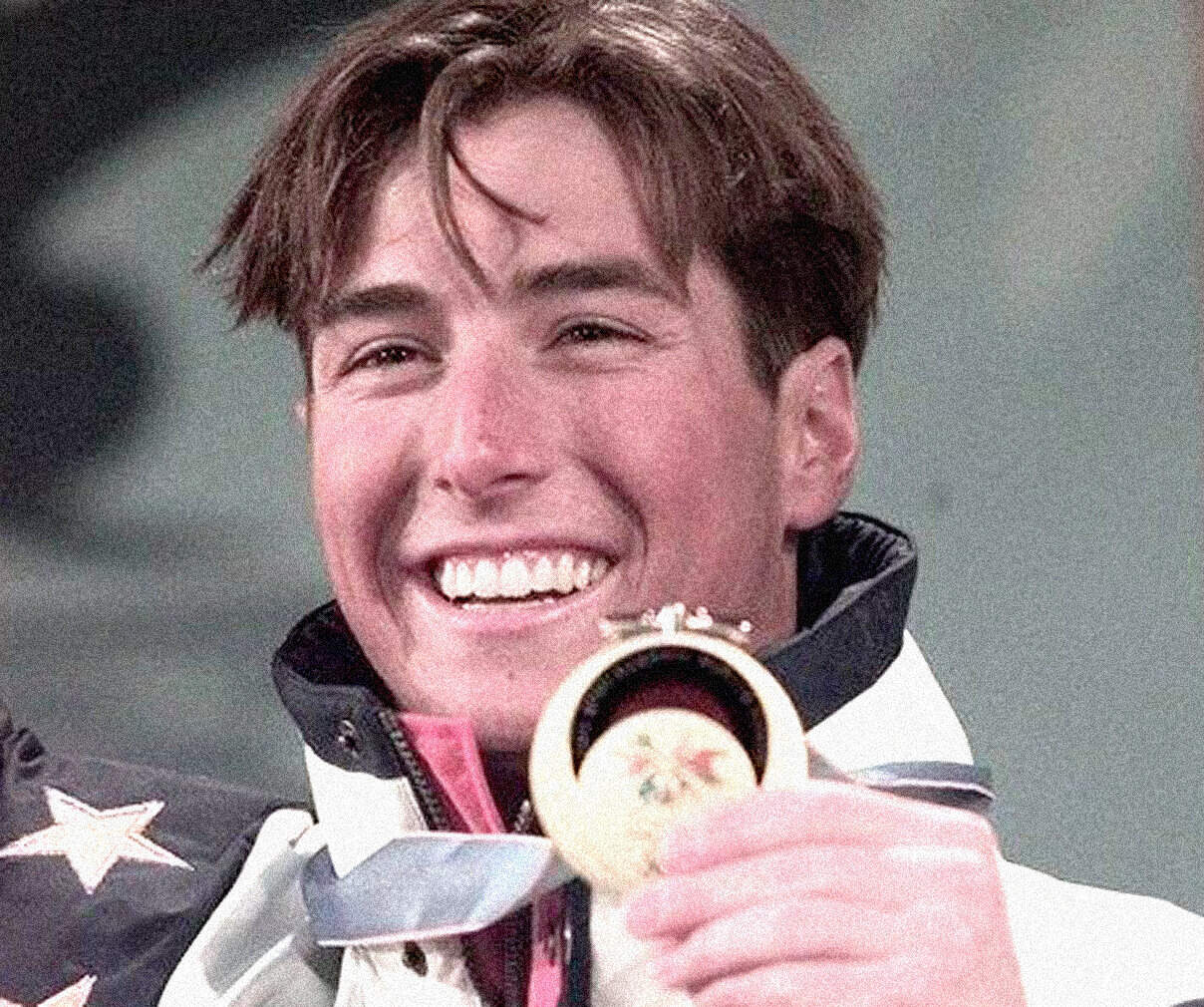 Celebratory athlete holding a gold medal, smiling with excitement, during a sports event, representing achievement and victory in the Olympics or a similar competition.
