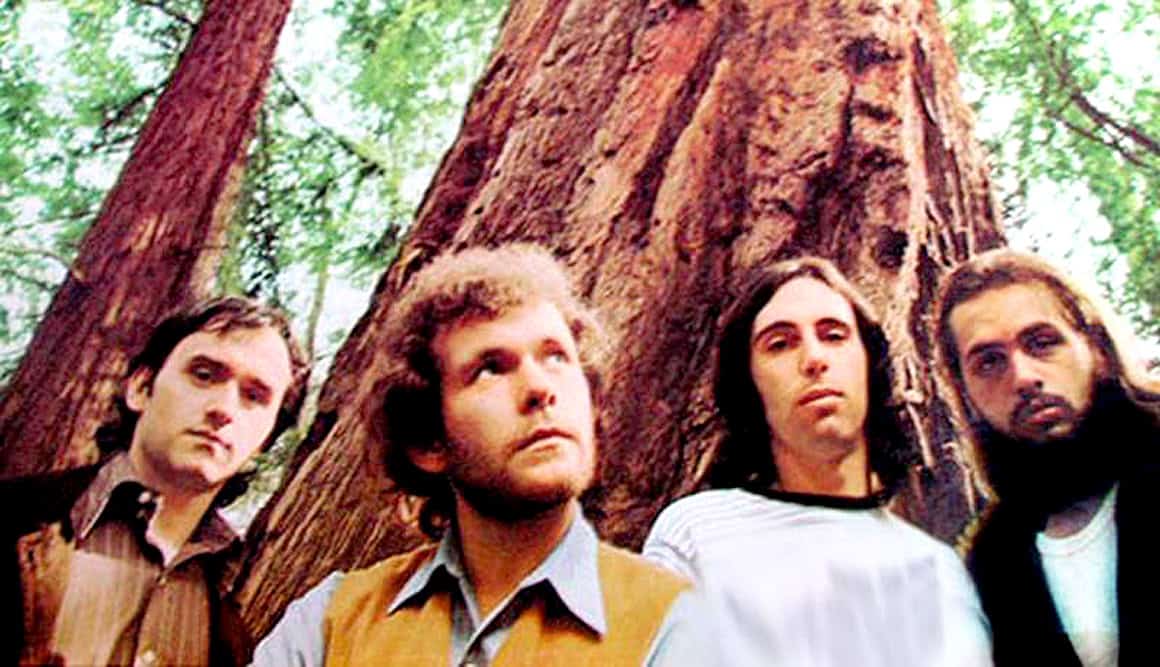 Vancouver, USA, 1984 - The band R.E.M. performing outdoors in front of a large, majestic redwood tree as part of a historical music event, showcasing alternative rock roots and music history.