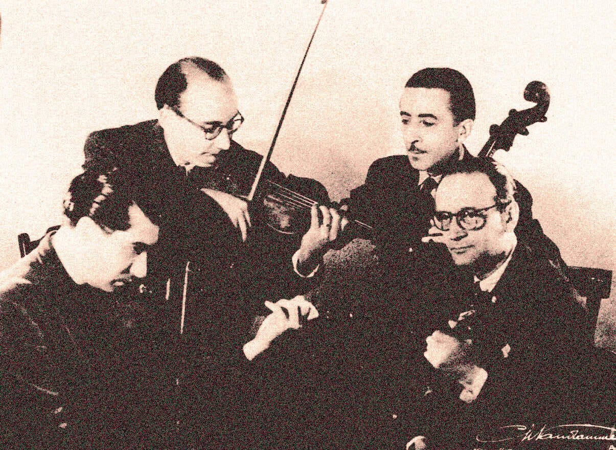 Vintage photo of four musicians playing string instruments, capturing a historical moment in music history. Perfect for archives or nostalgic music content.