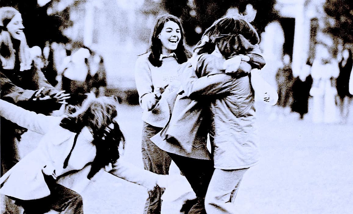 Joyful women hugging and laughing in a park, capturing moments of friendship and happiness, black and white photograph.