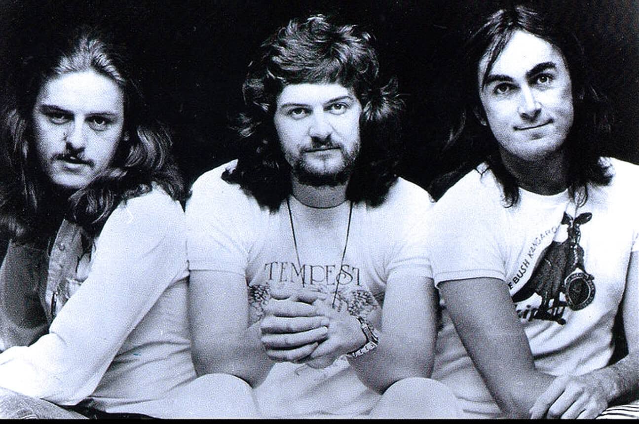 Vintage black and white photo of legendary rock band Queen, featuring Freddie Mercury, Brian May, and John Deacon, known for iconic hits and influential music history.