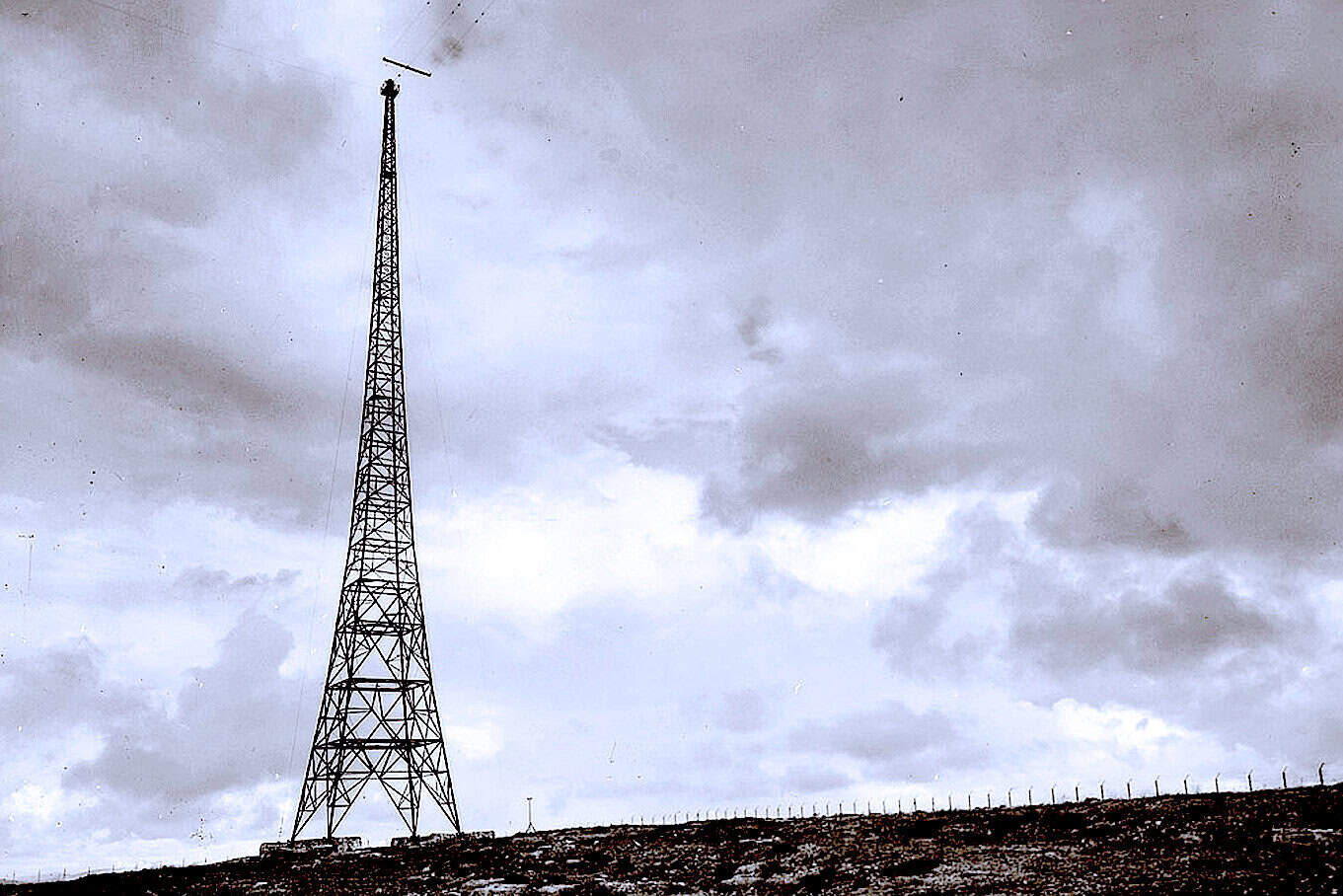 High-voltage radio tower on a cloudy sky, symbolizing communication infrastructure.