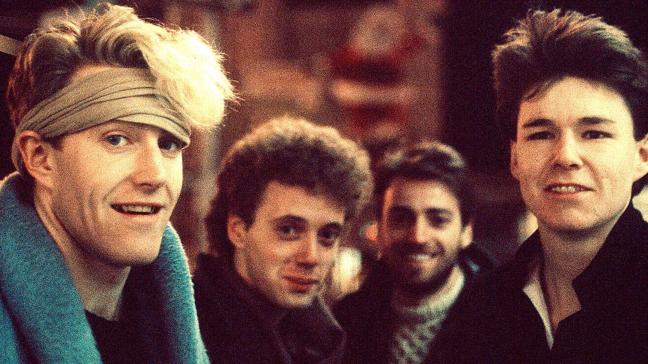 Vintage 1980s pop band members in casual attire, with iconic hairstyles, enjoying a social event, highlighting music history and cultural nostalgia.