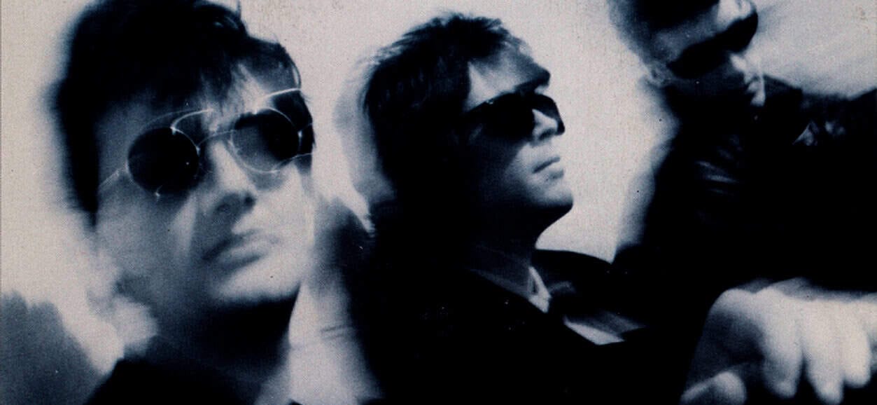 Black and white photo of three stylish individuals wearing sunglasses, reflecting 1980s fashion and music culture, associated with past music archives and historical sound recordings.