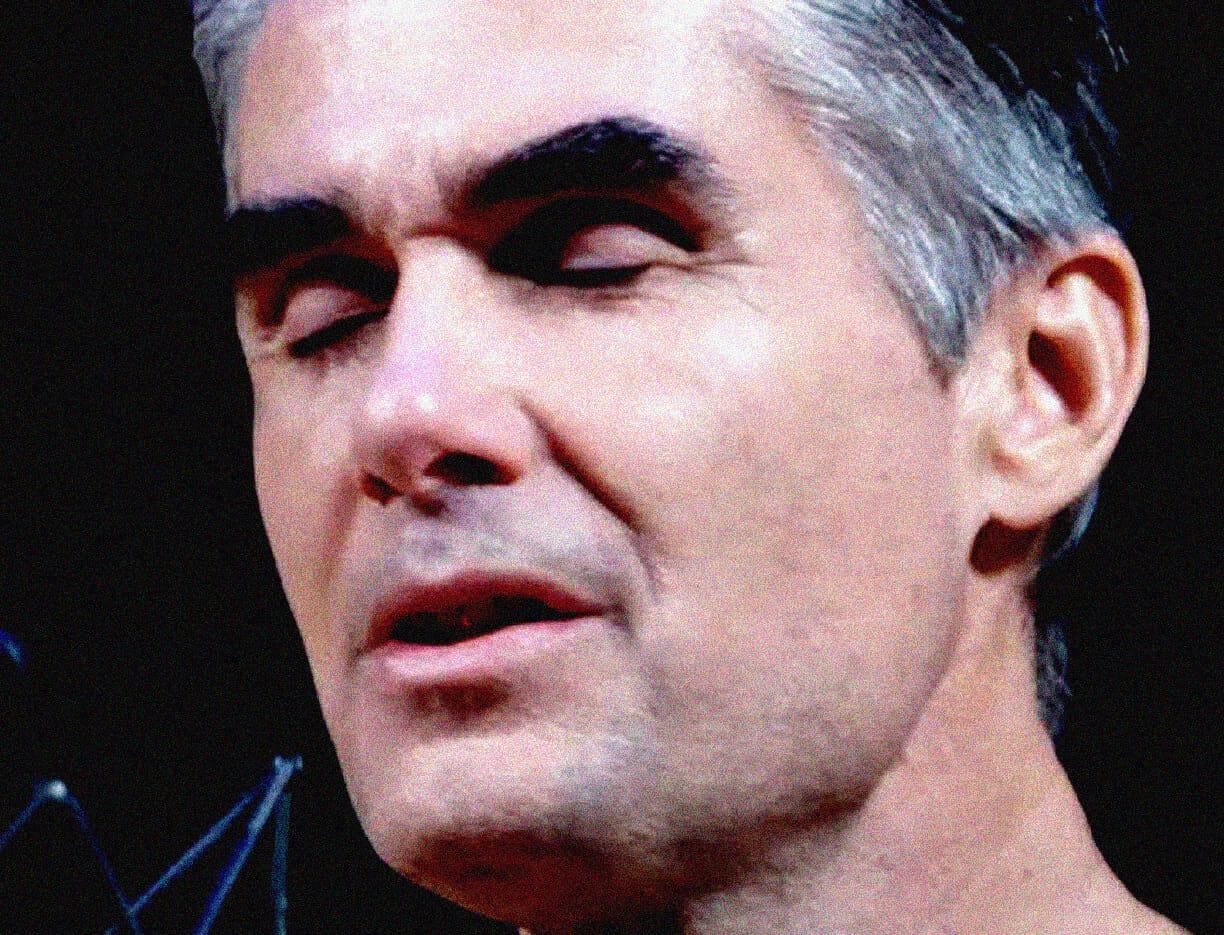Close-up of a man with gray hair and closed eyes expressing emotion, possibly during a speech or performance, representing historical moments, news, and music archives.
