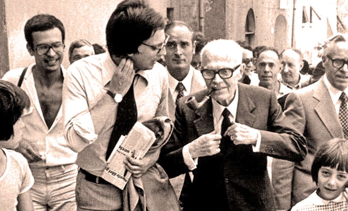 Intellectuals and journalists gather on the street, engaging in conversation during a historical public event, with some smoking pipes and holding newspapers, capturing a moment of cultural and political significance.
