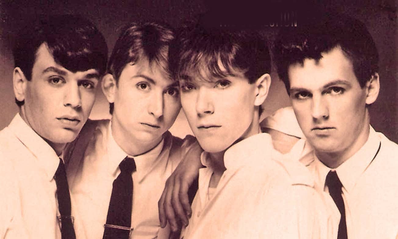 Four young men in matching white shirts and black ties posing for a vintage photo, classic band look, 1980s music, boy band, nostalgic music memory.