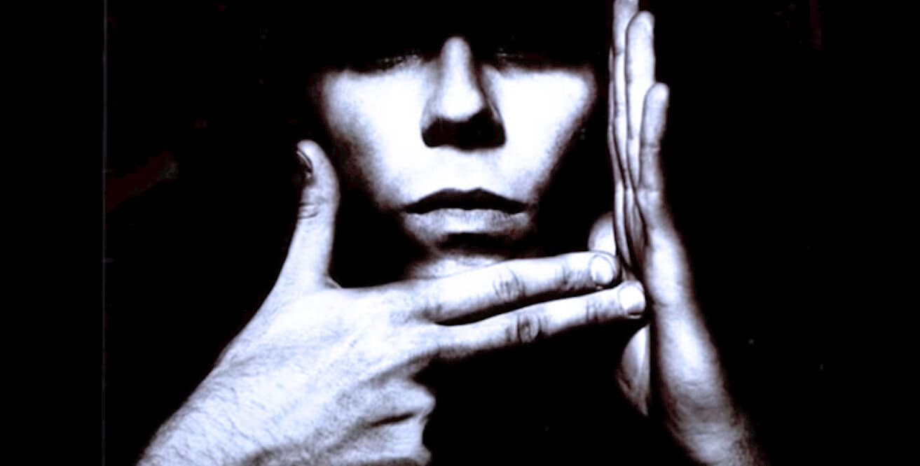 Mysterious person with hands framing face in black and white photo, artistic portrait emphasizing expression and emotion, ideal for history and music archive content.