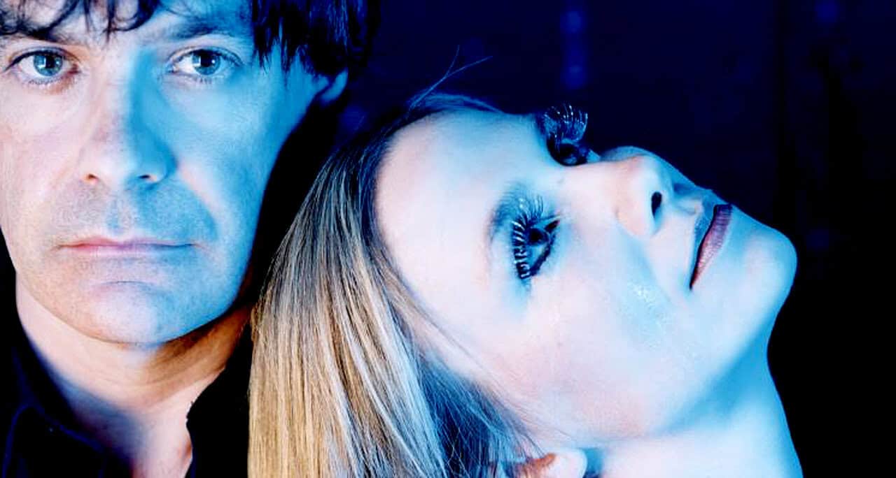 Close-up of a young man and woman with contrasting expressions, illuminated by blue lighting, emphasizing modern music and sound archive themes of Past Daily.