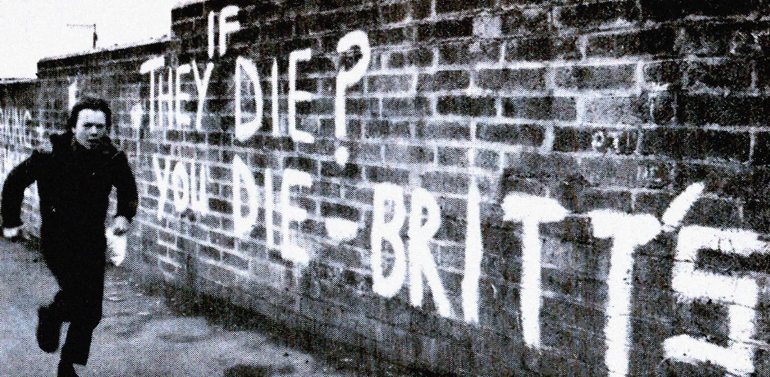 Youth Movement graffiti mural on brick wall, urban street art, black and white photo of a young man running past a bold painted message, reflecting cultural history and activism.