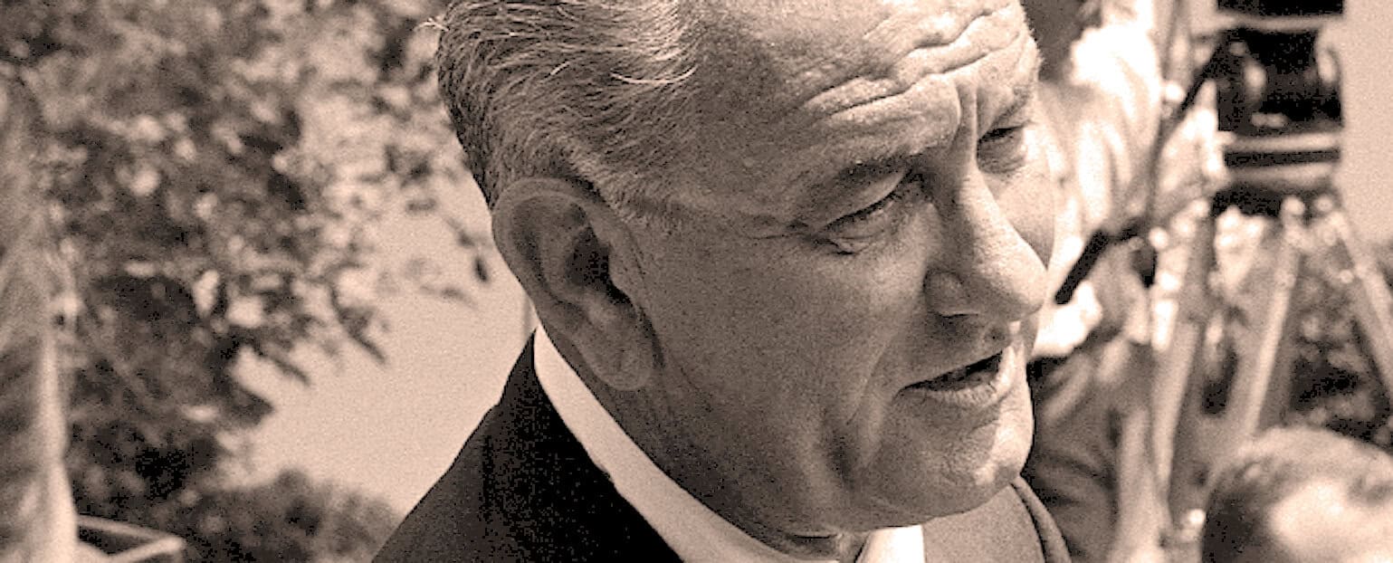 Historical black and white photo of a man speaking outdoors, symbolizing news, history, and classic media moments from the Past Daily sound archive.