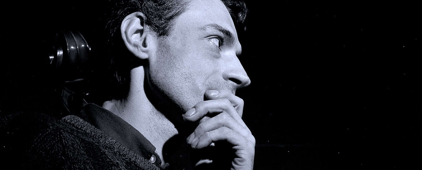 Thoughtful man with hand on chin, contemplating, in black and white photo reflecting introspection and creativity.