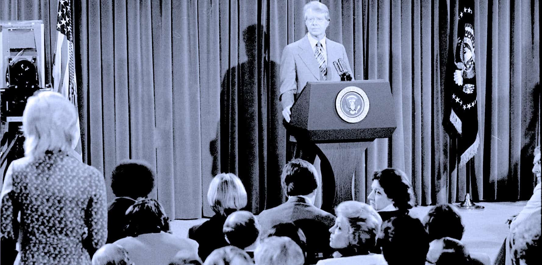 News conference with President Lyndon B. Johnson at the podium, surrounded by American flags and curtains, historical political event, archive footage, vintage broadcast image, historic American leadership, pastdaily archive.