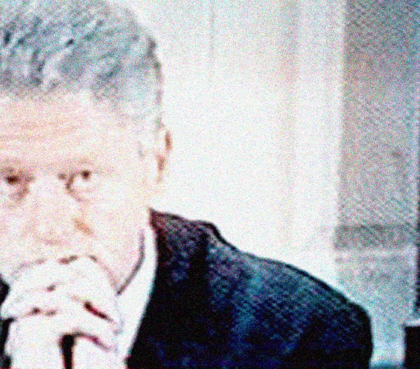 Close-up of a woman with gray hair reading a newspaper, representing historical news archival media.