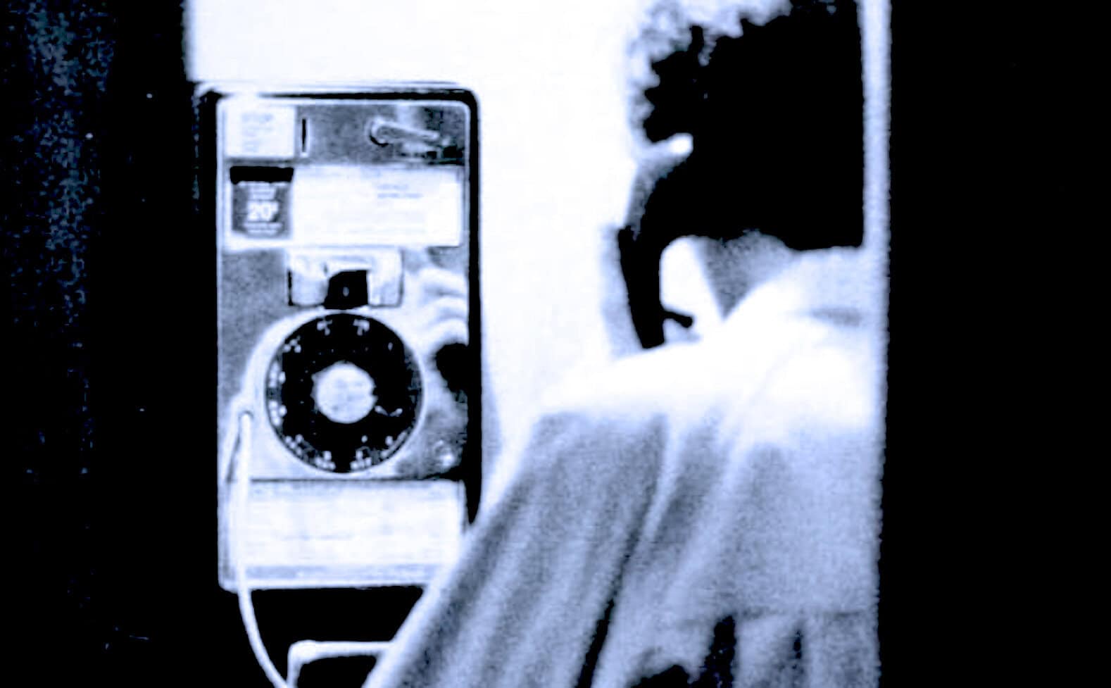 Vintage public telephone booth with a rotary dial, black-and-white photo capturing nostalgic communication history.