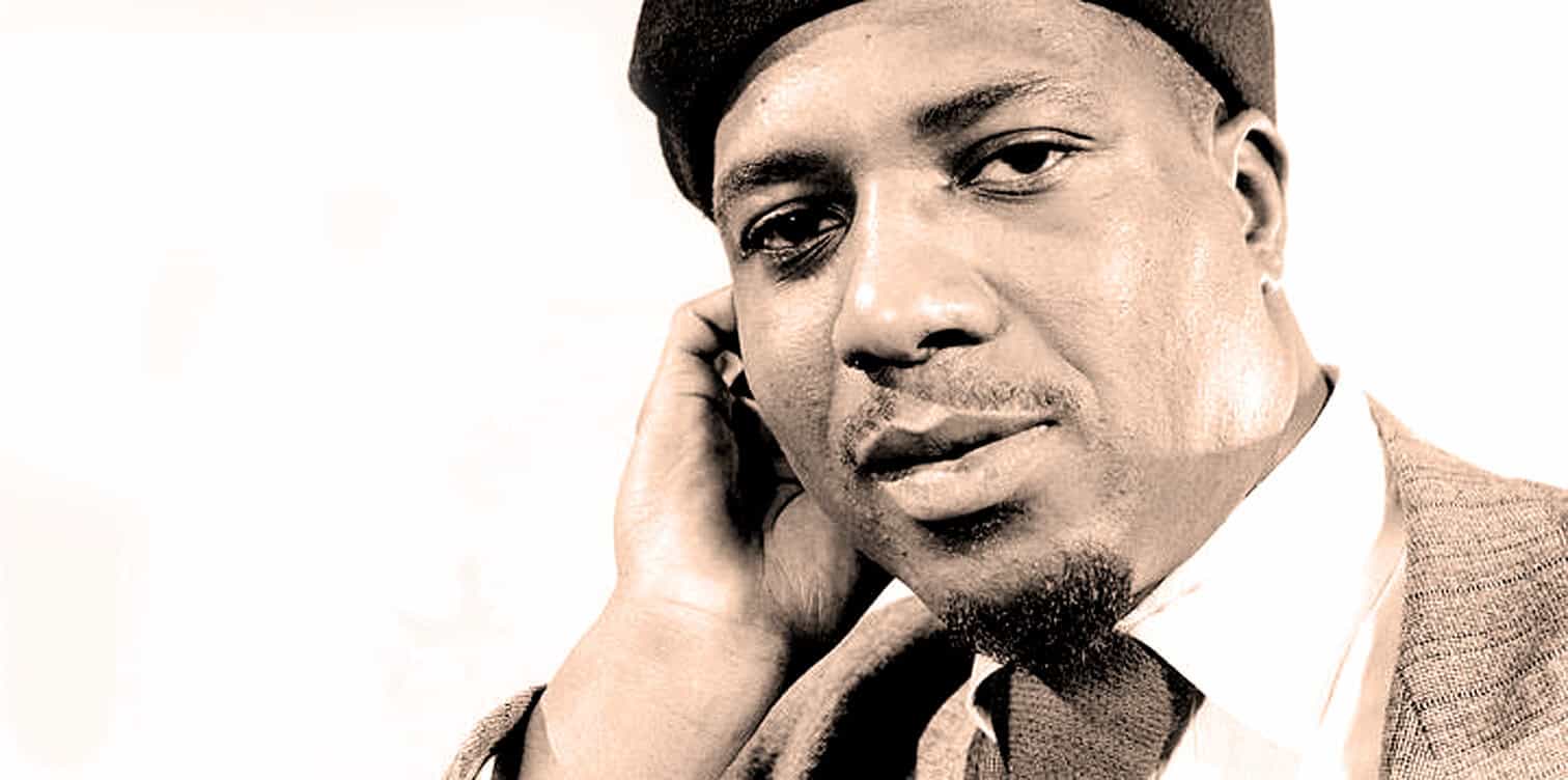 Black man wearing a suit with a vintage style, close-up portrait, historical figure, 20th-century media personality, evocative of classic news and music archive imagery.