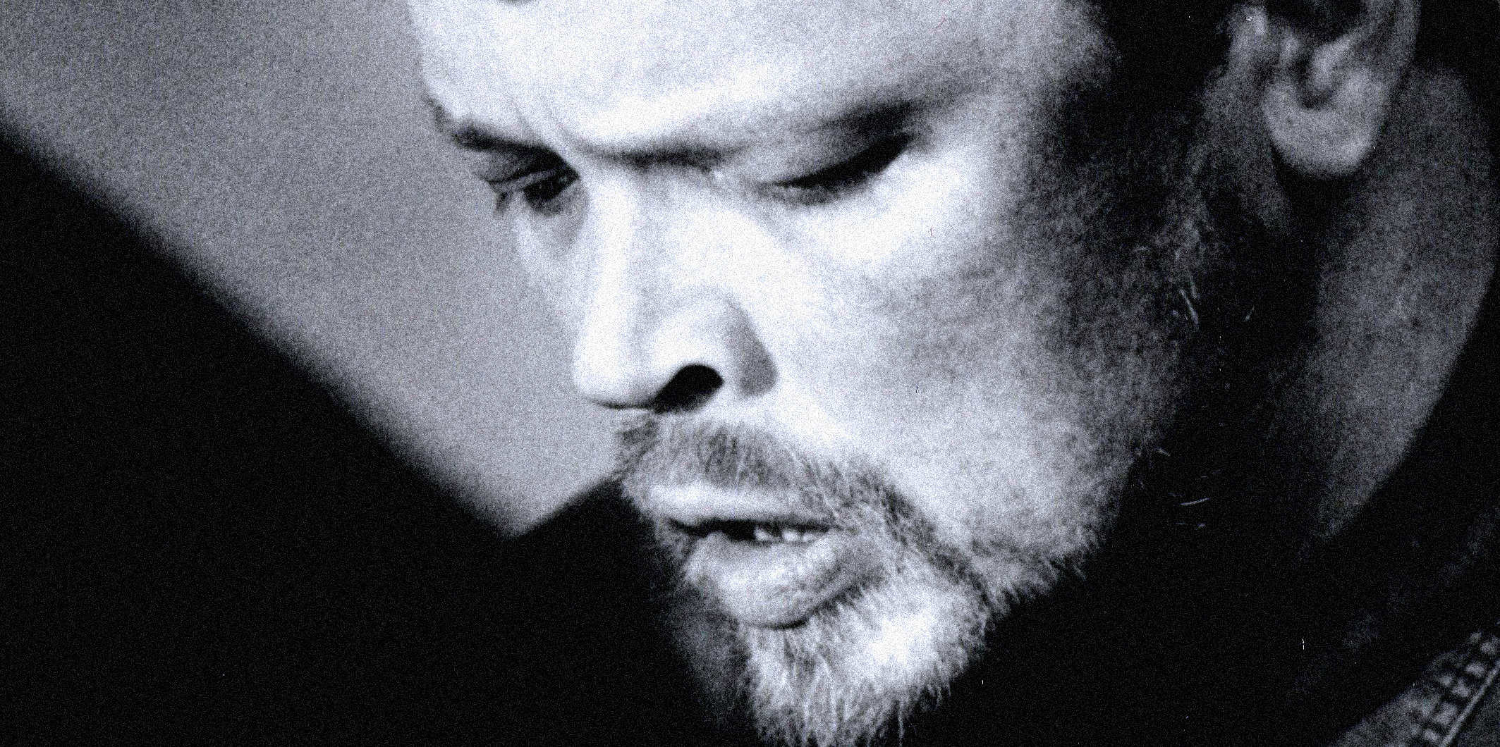 Old black and white photograph of a man with a beard, focusing on his contemplative face, illustrating nostalgia and history, suitable for a sound archive of news, music, and historic recordings.