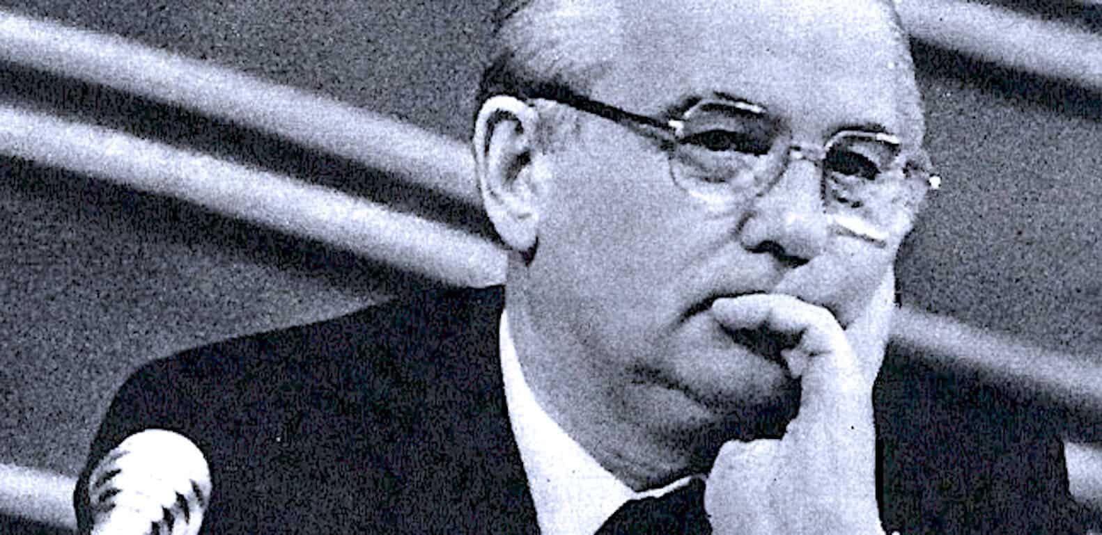 Thoughtful man with glasses, historical figure, in black and white promotional photo, symbolizing news, history, and music archives.