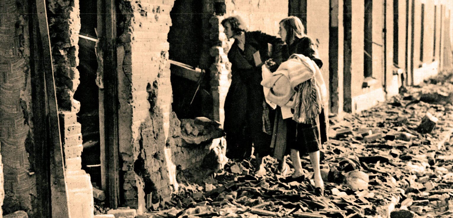 Ruined building with debris, women and children observing destruction, historical destruction scene, war aftermath, historical news archive, vintage photograph.