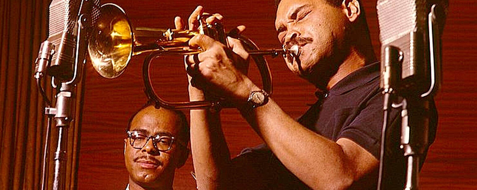 Vintage jazz recording session featuring a trumpeter passionately playing the trumpet in a professional studio.