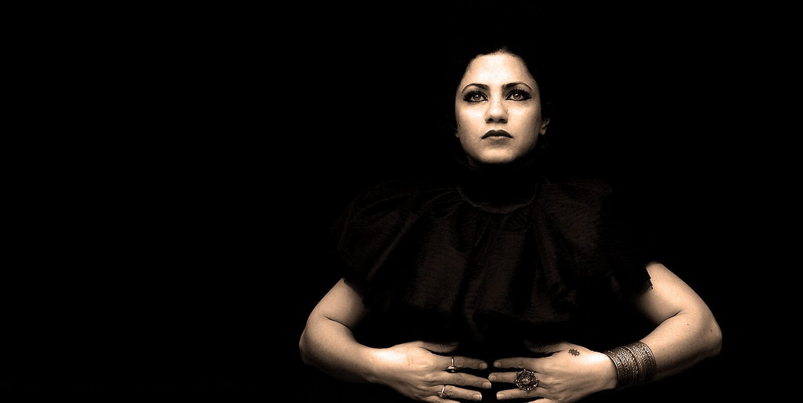 Elegant woman with dark makeup and jewelry, fashion portrait, black background, artistic photography.