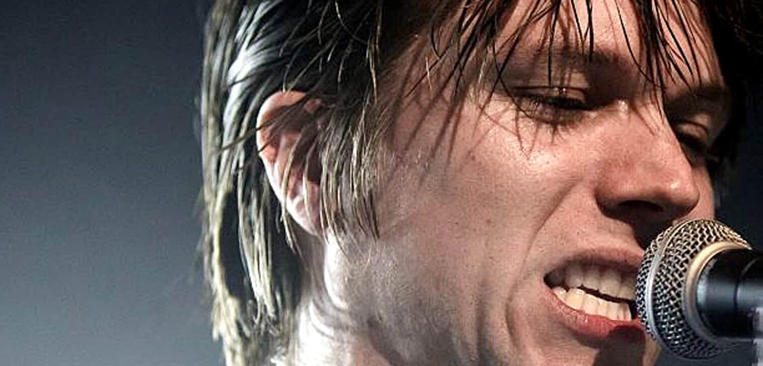 Close-up of a male singer passionately performing into a microphone, showcasing music history, live performance, and legendary artist themes.