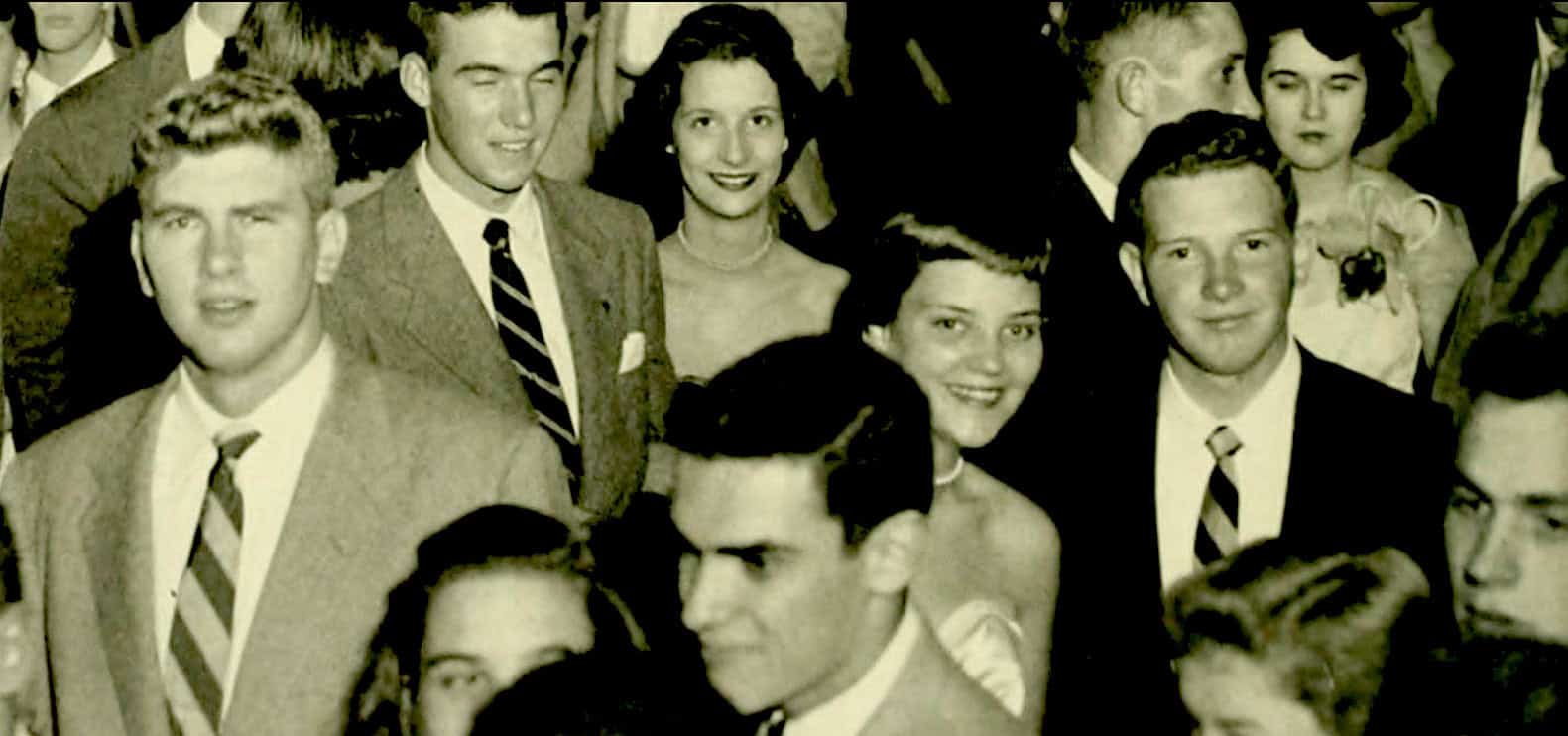 Vintage black and white photo of young adults at a social gathering, showcasing mid-20th century fashion, ideal for archives on news, history, music, and cultural events.