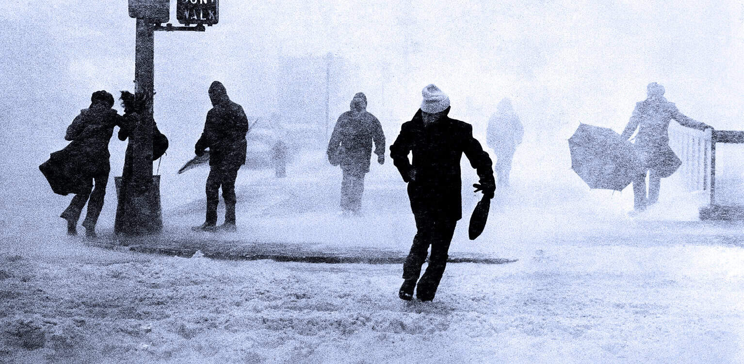 Snowstorm with people waiting under umbrellas and walking through heavy snow, illustrating weather news and urban life, captured in a black-and-white photo.
