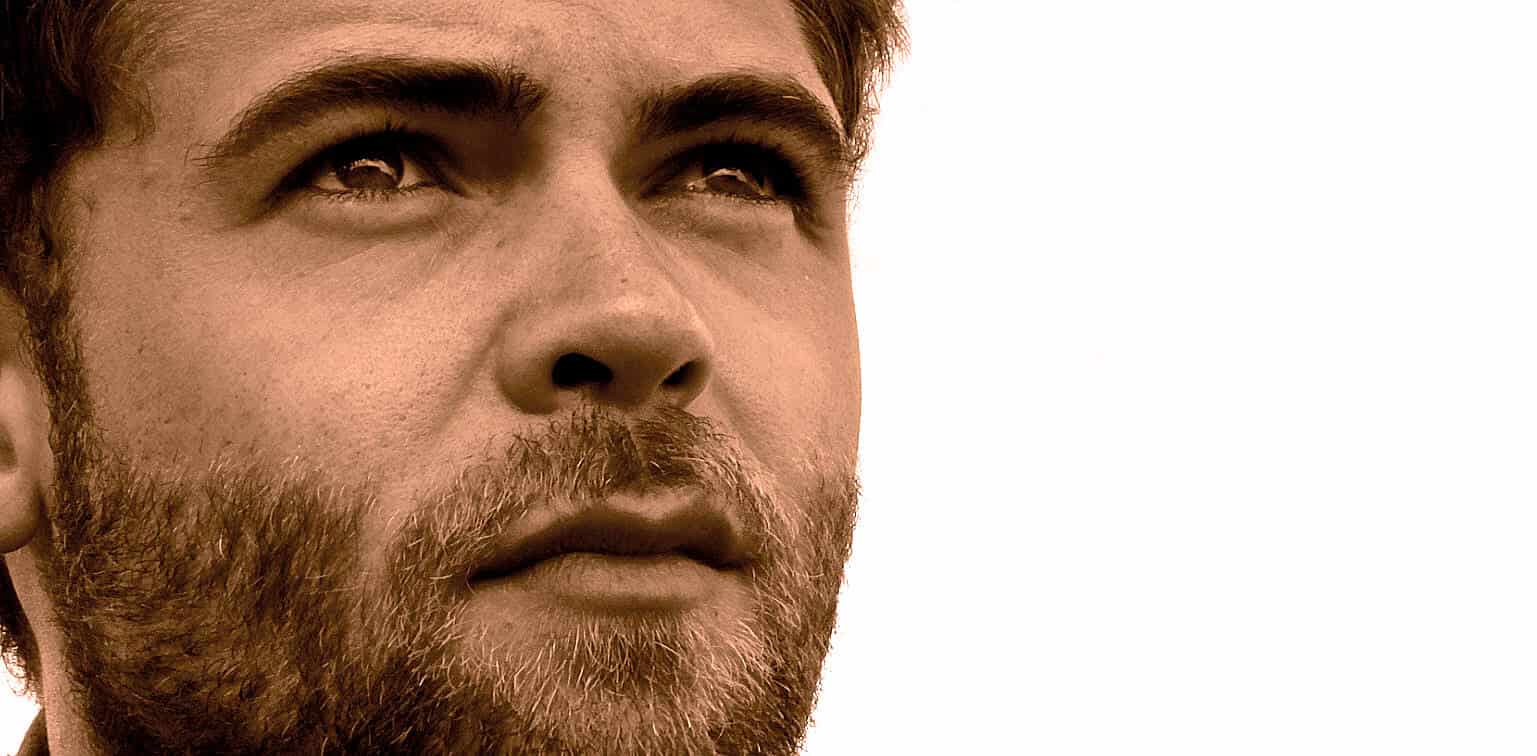 Close-up of a young man's face with a beard, highlighting themes of music, news, history, and sound archives.