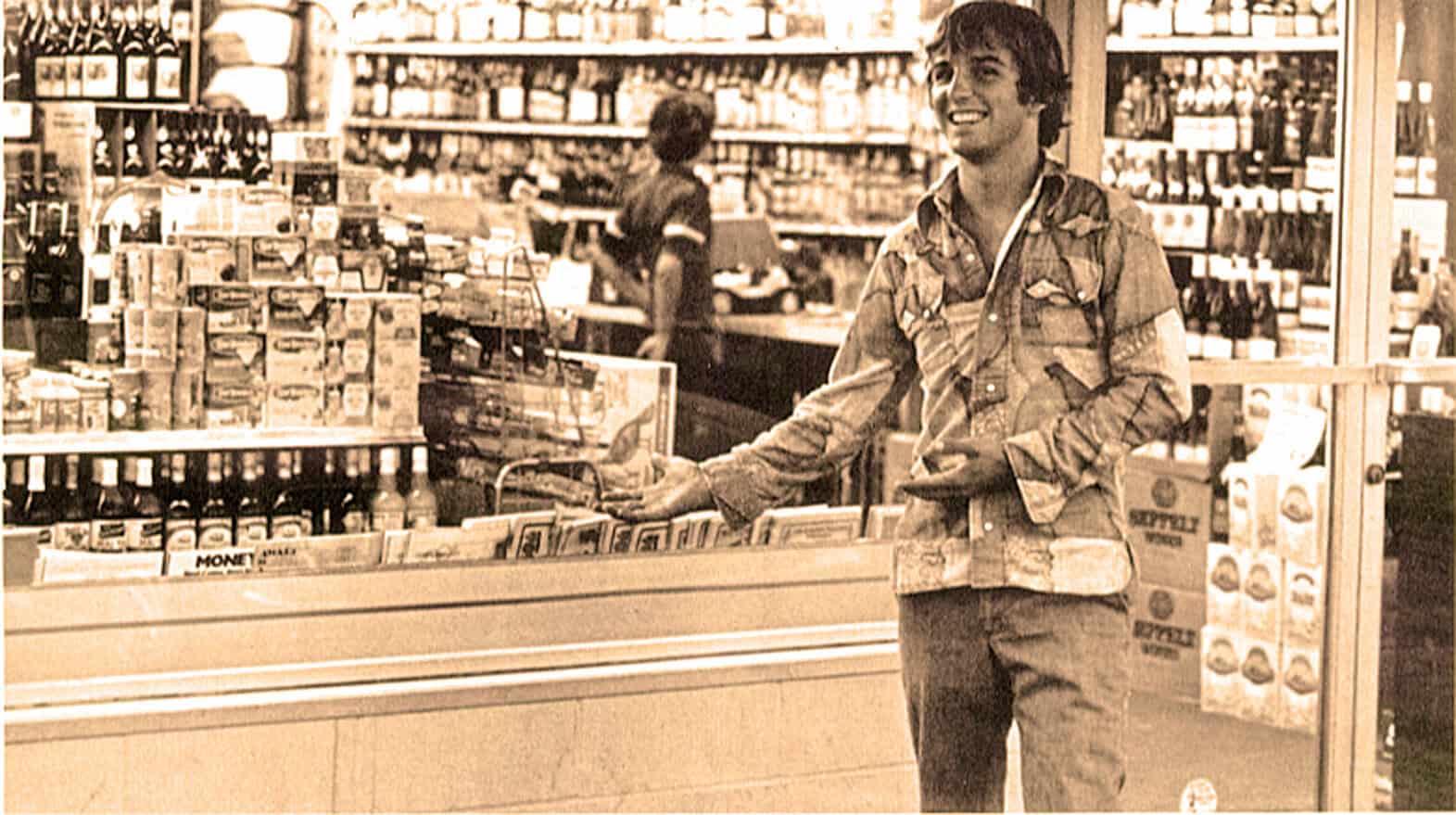 A young man shopping in a grocery store with shelves stocked with canned goods and beverages, capturing a moment of everyday life and consumer culture.