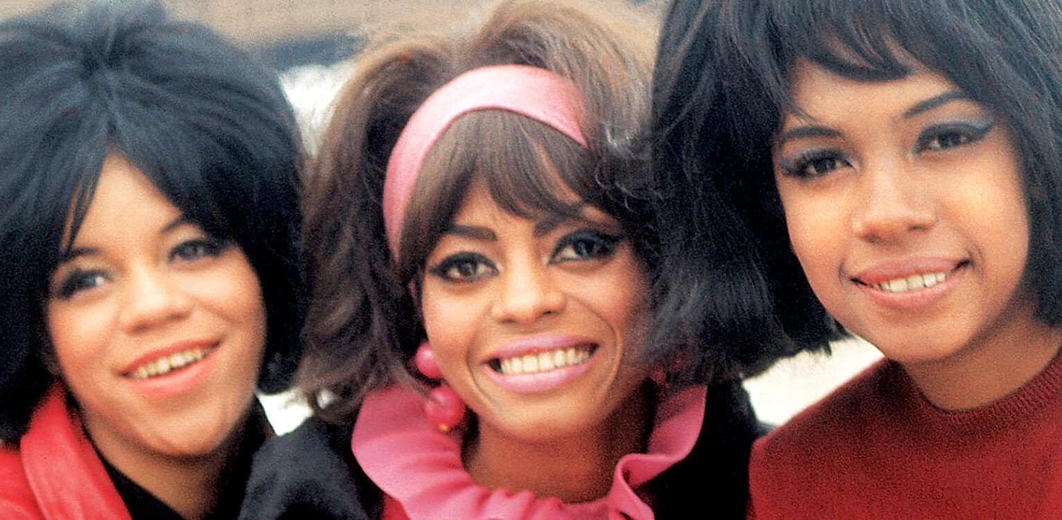 Vintage music group The Supremes, featuring Diana Ross, smiling in colorful 1960s attire - iconic Motown female vocal ensemble.