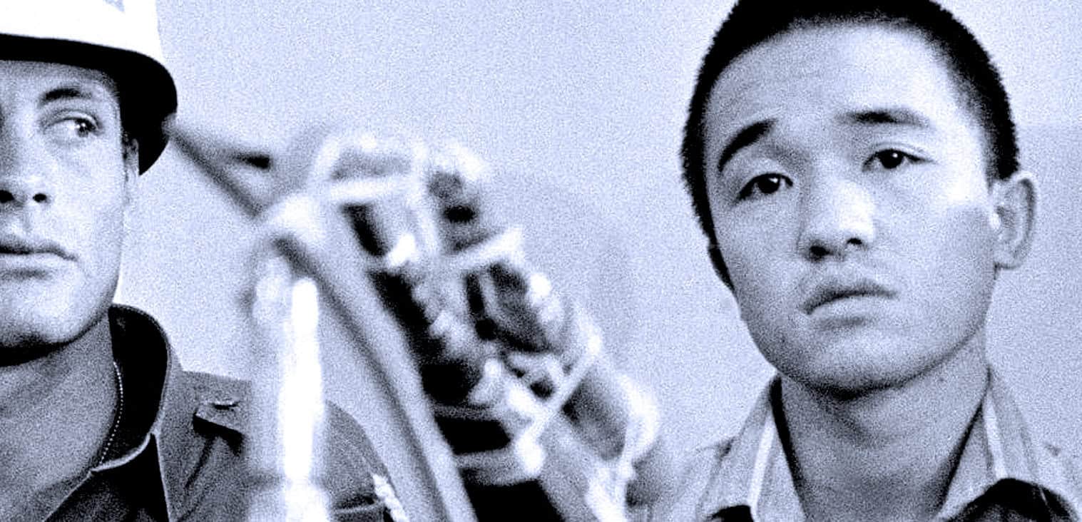 A black and white photo of two young men, one wearing a hat and the other with a serious expression, with a focus on news and music archive relevance.