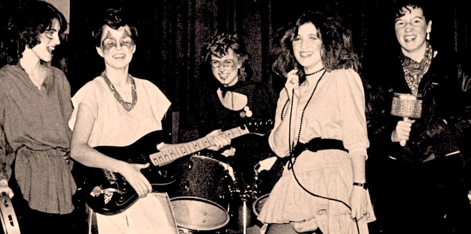 Vintage band photo featuring female musicians and a drummer at a live music event.